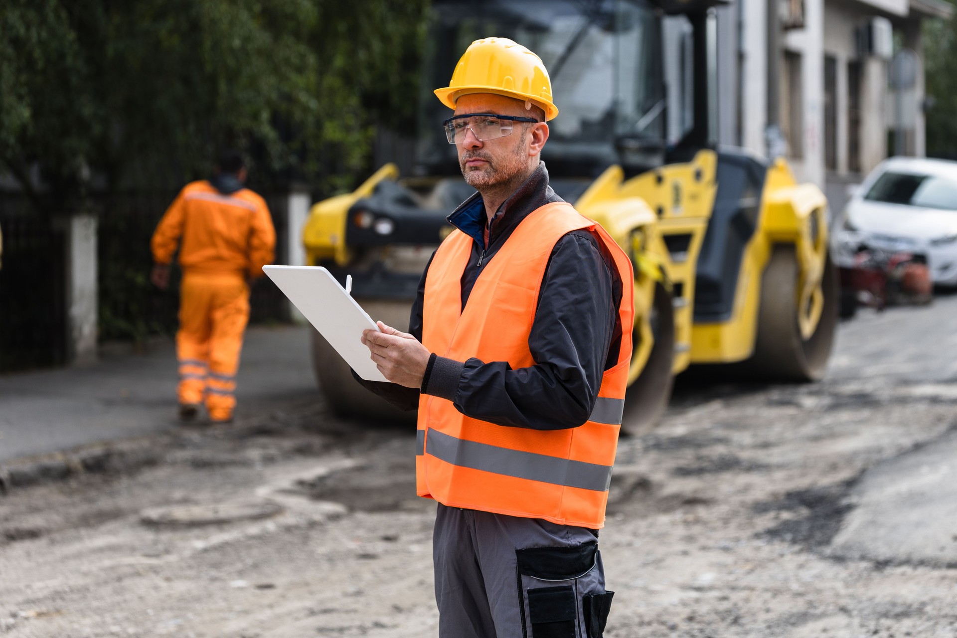 Construction supervisor reviewing plans while overseeing roadwork in an urban area during the day
